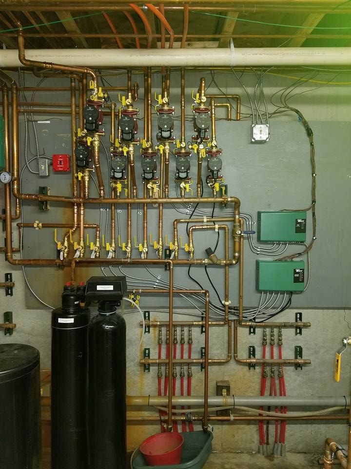 Copper pipes and valves against a concrete wall, likely a home's hydronic heating system.