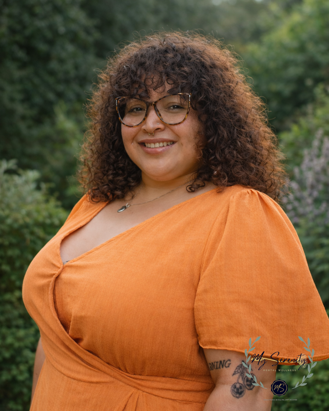 Woman in a blazer and white shirt smiles at the camera, with a fluffy afro.