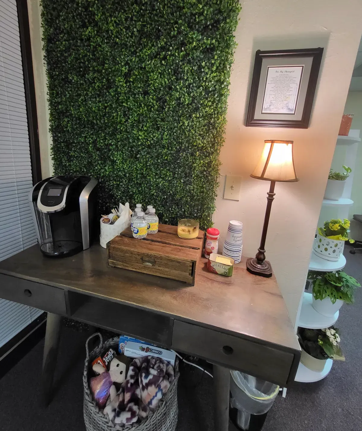 A desk with a keurig coffee maker and a lamp on it.