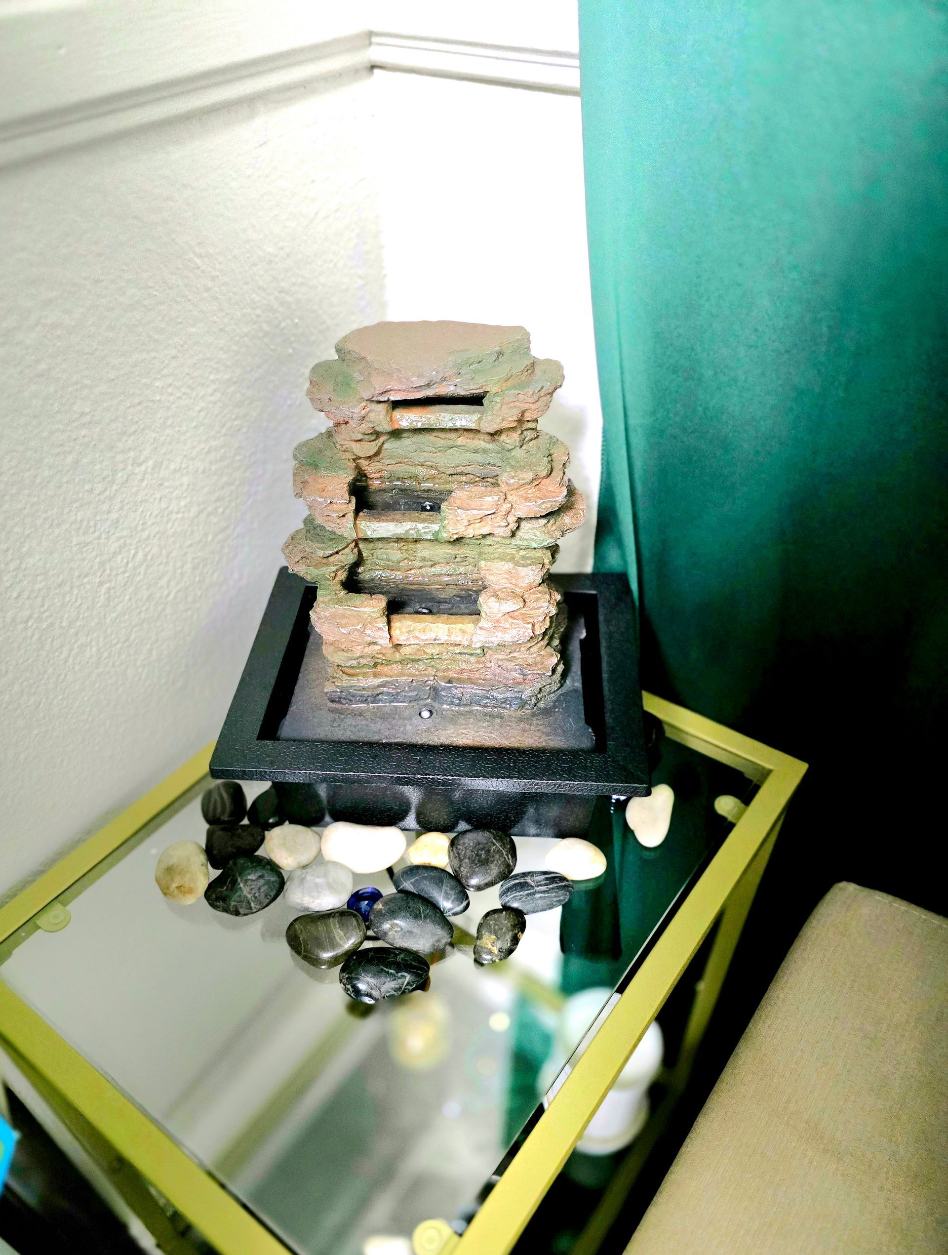 A small water fountain sits on a glass table
