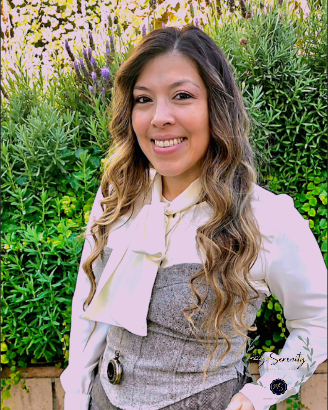 Woman with long highlighted hair smiles in a light blue striped button-up shirt outdoors.