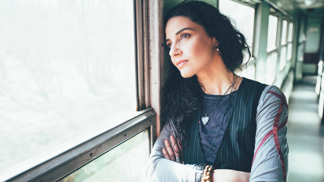 A woman is leaning against a window on a train.