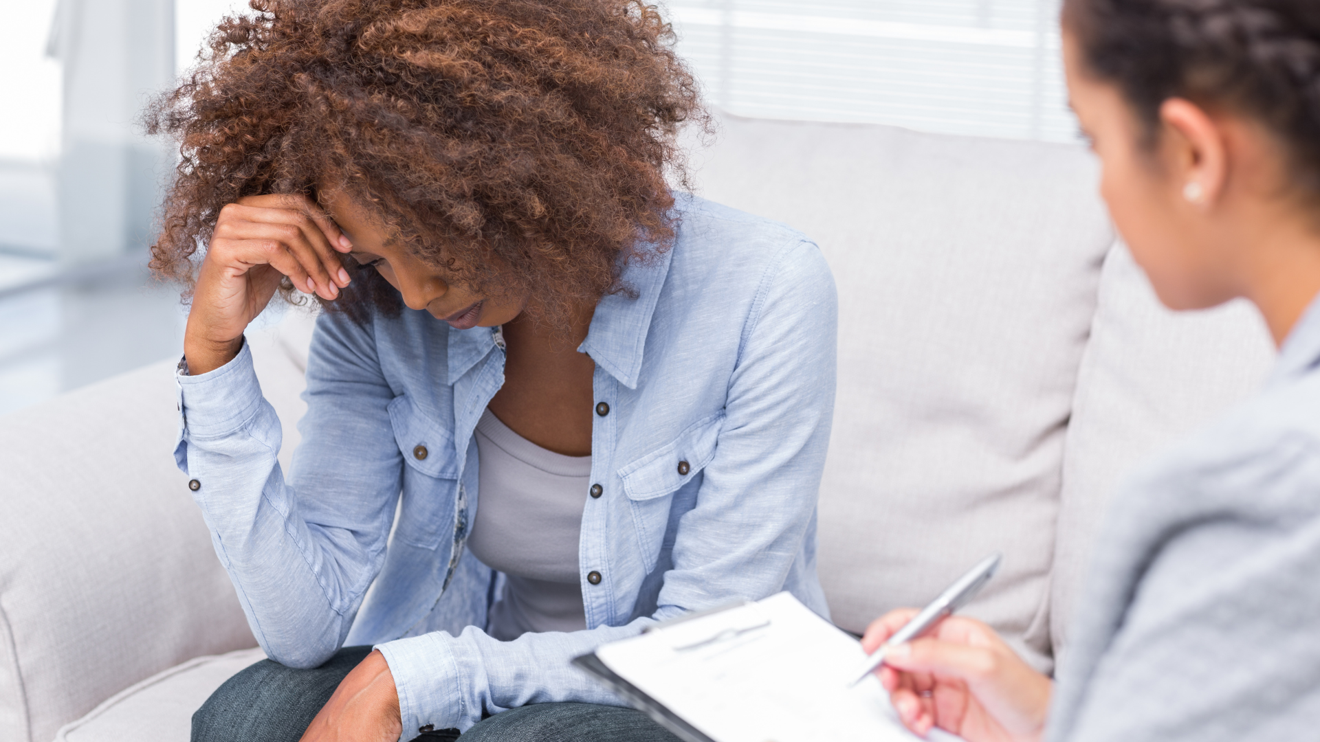 A woman is sitting on a couch talking to a therapist.