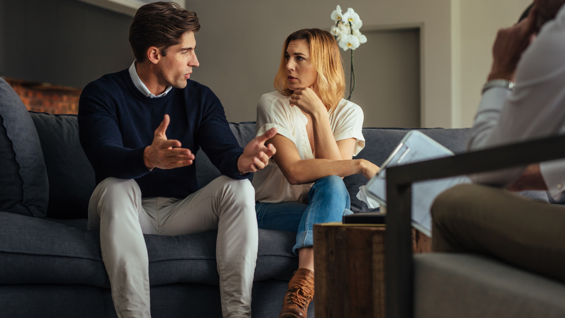 A man and a woman are sitting on a couch talking to a doctor.