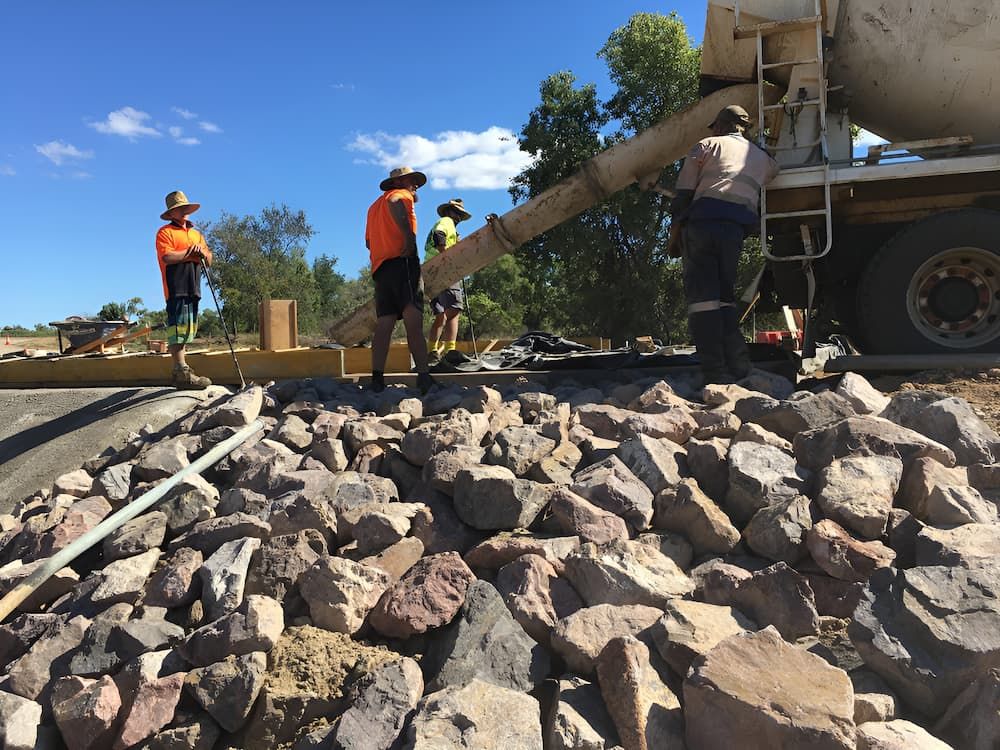 A Cement Truck Is Pouring Cement Into A Pile Of Rocks — S & K Raw Materials & Earthmoving in Atherton, QLD