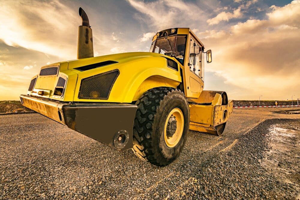 A Yellow Road Roller Is Sitting On Top Of A Gravel Road — S & K Raw Materials & Earthmoving in Georgetown, QLD