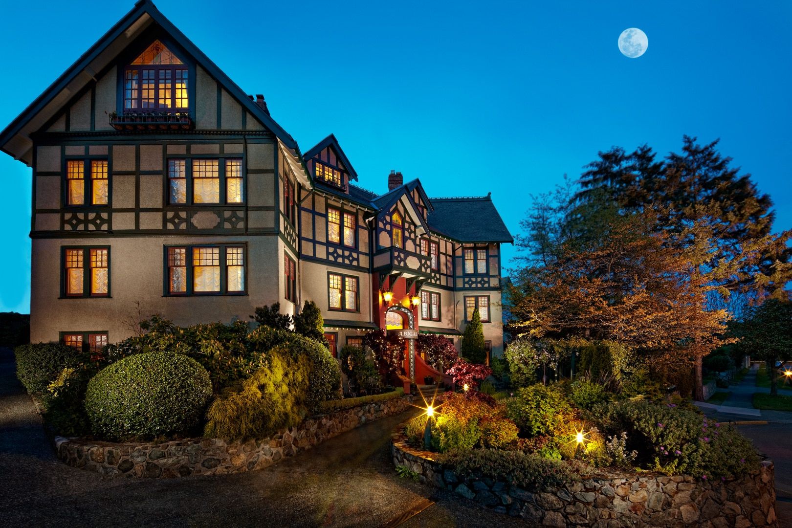 Abigail's Hotel lit up at night with a full moon in the background