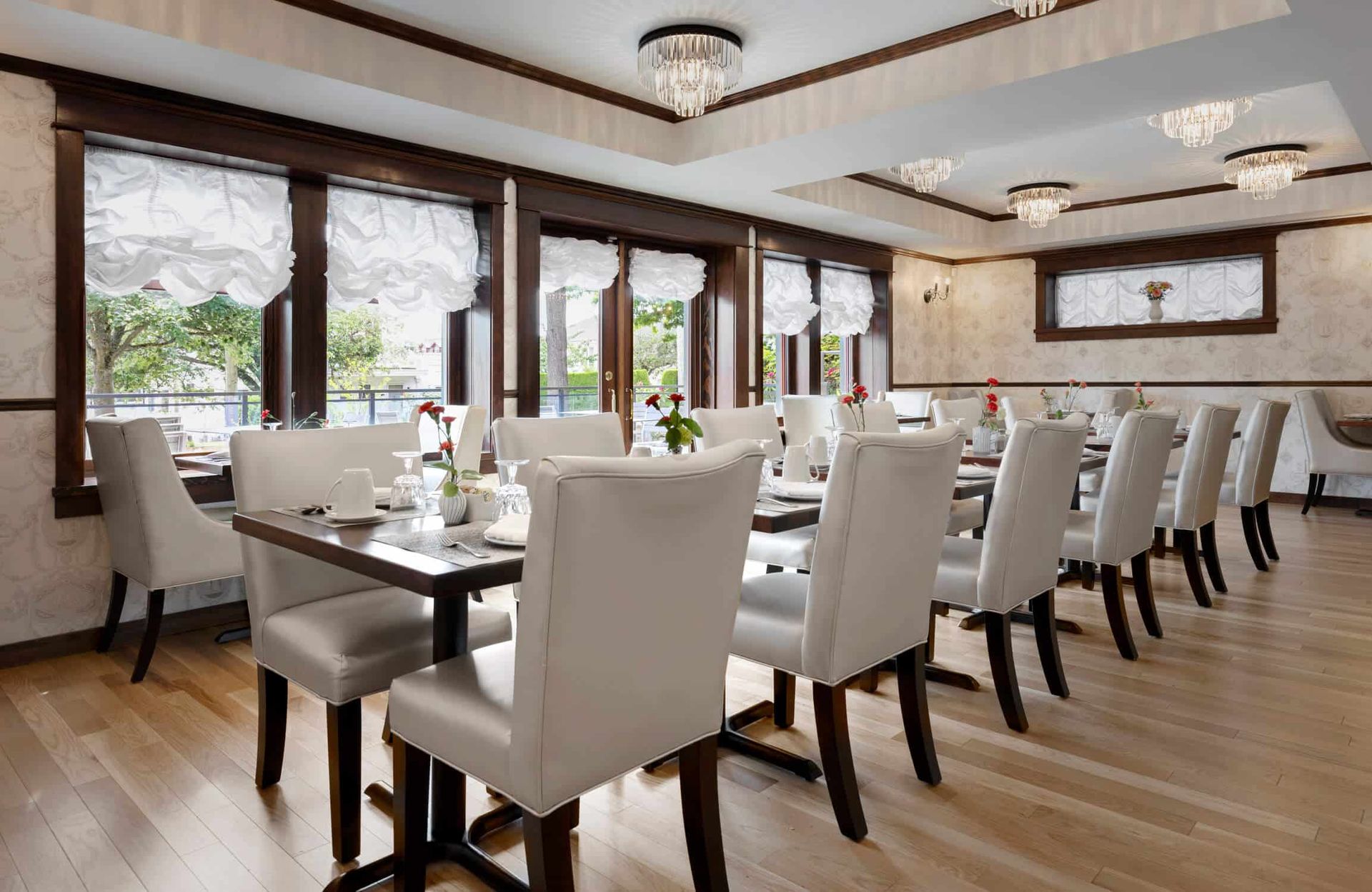 A dining room with tables and chairs and lots of windows.