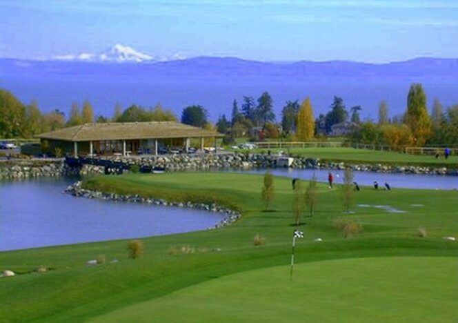 A golf course with a lake and mountains in the background.