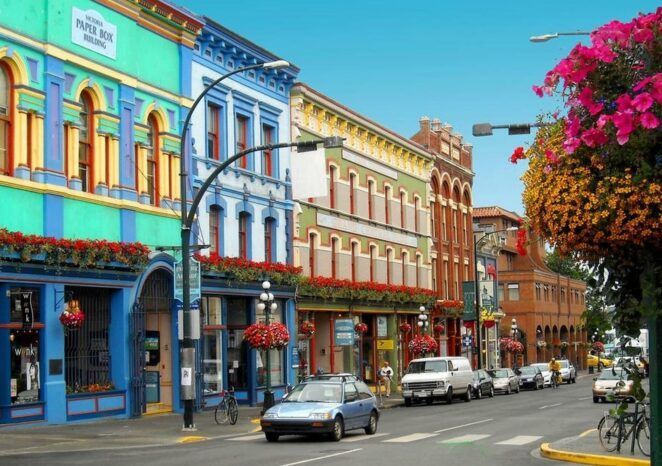 A blue car is driving down a street lined with colorful buildings