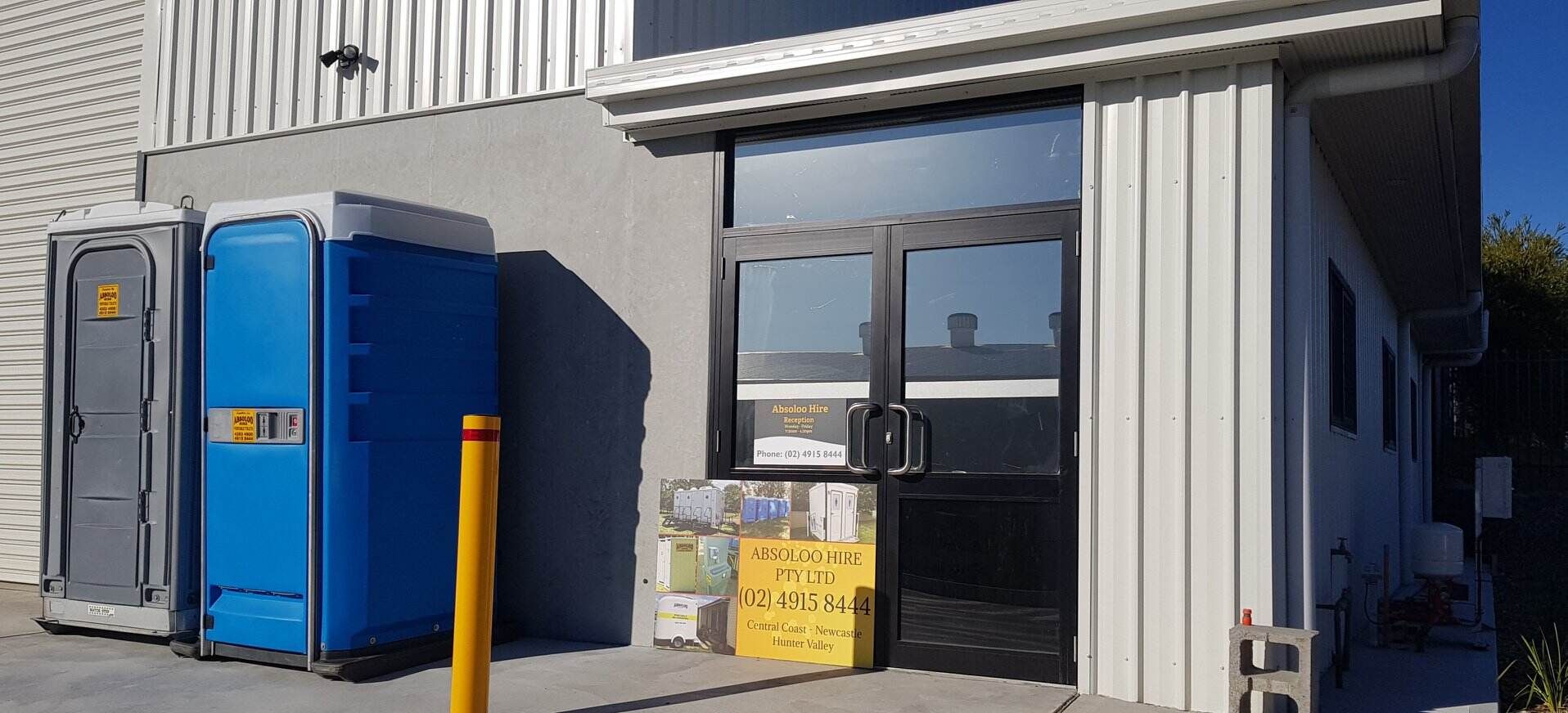 Two Portable Toilets Are Parked in Front of a Building — Absoloo Hire Pty Ltd in Forster, NSW