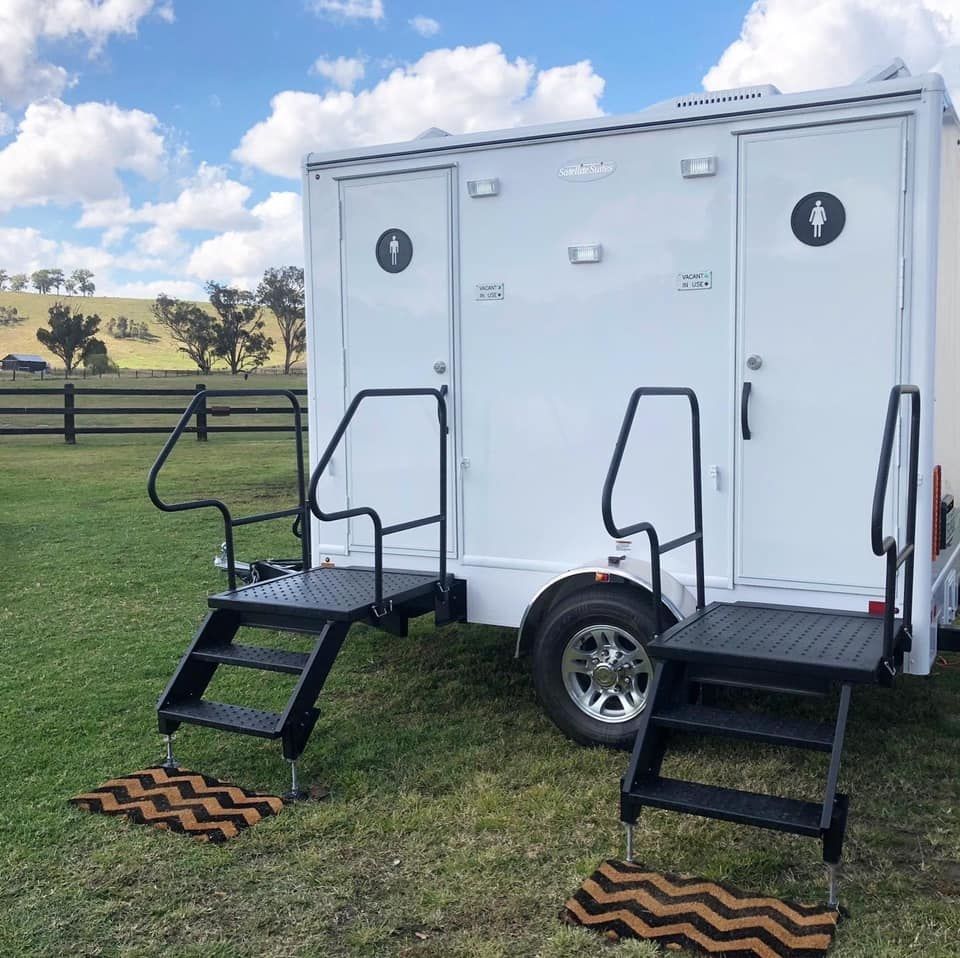 A Toilet With Stairs Attached to It is Parked in a Grassy Field — Absoloo Hire Pty Ltd in Hunter Valley, NSW