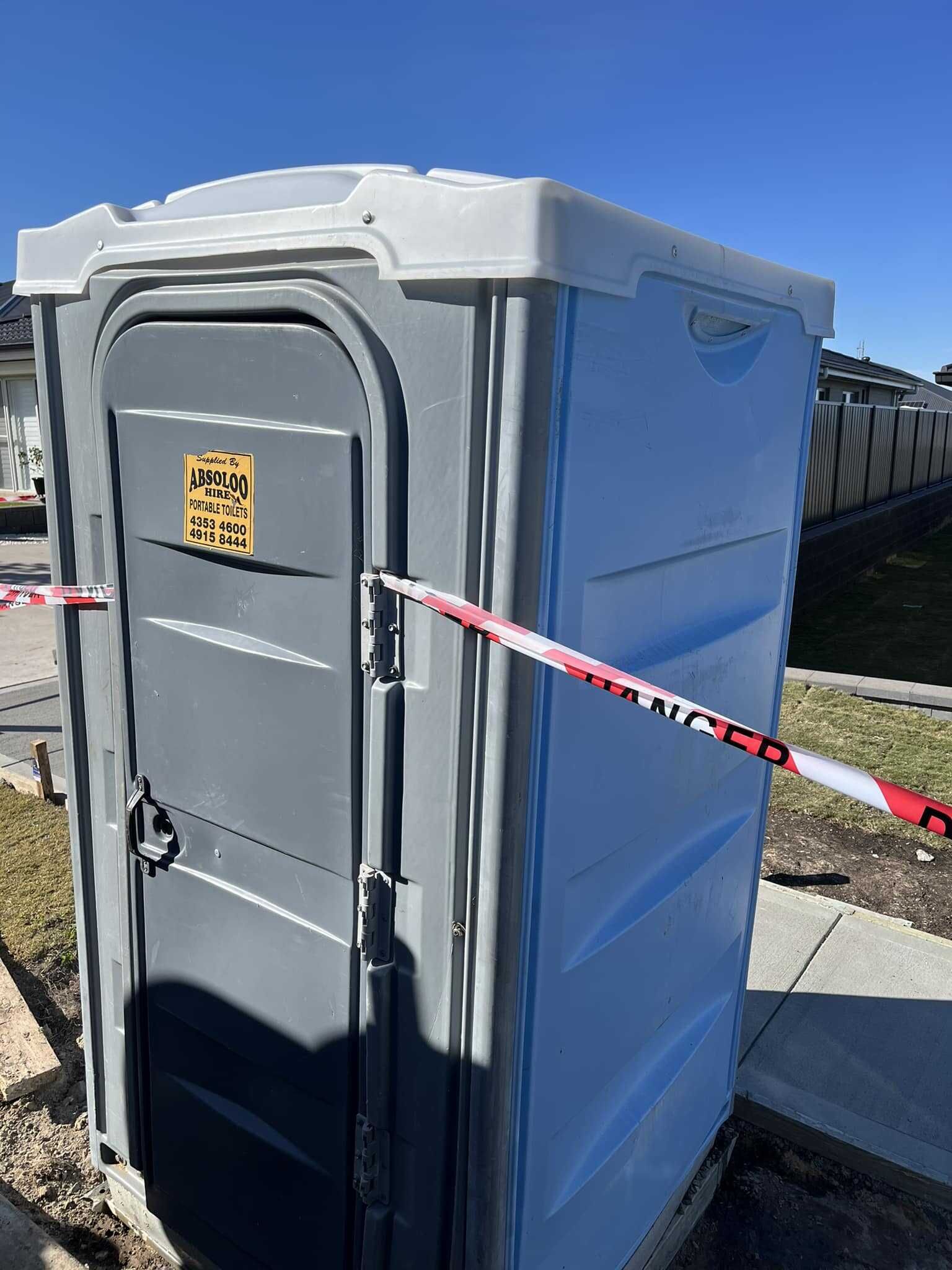 A Portable Toilet is Sitting on the Side of the Road — Absoloo Hire Pty Ltd in Forster, NSW