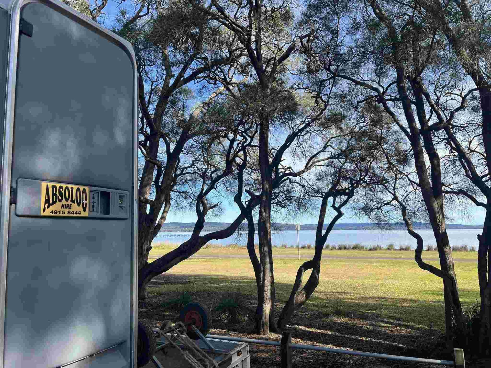 A Portable Toilet is Parked in a Field — Absoloo Hire Pty Ltd in Wyong, NSW