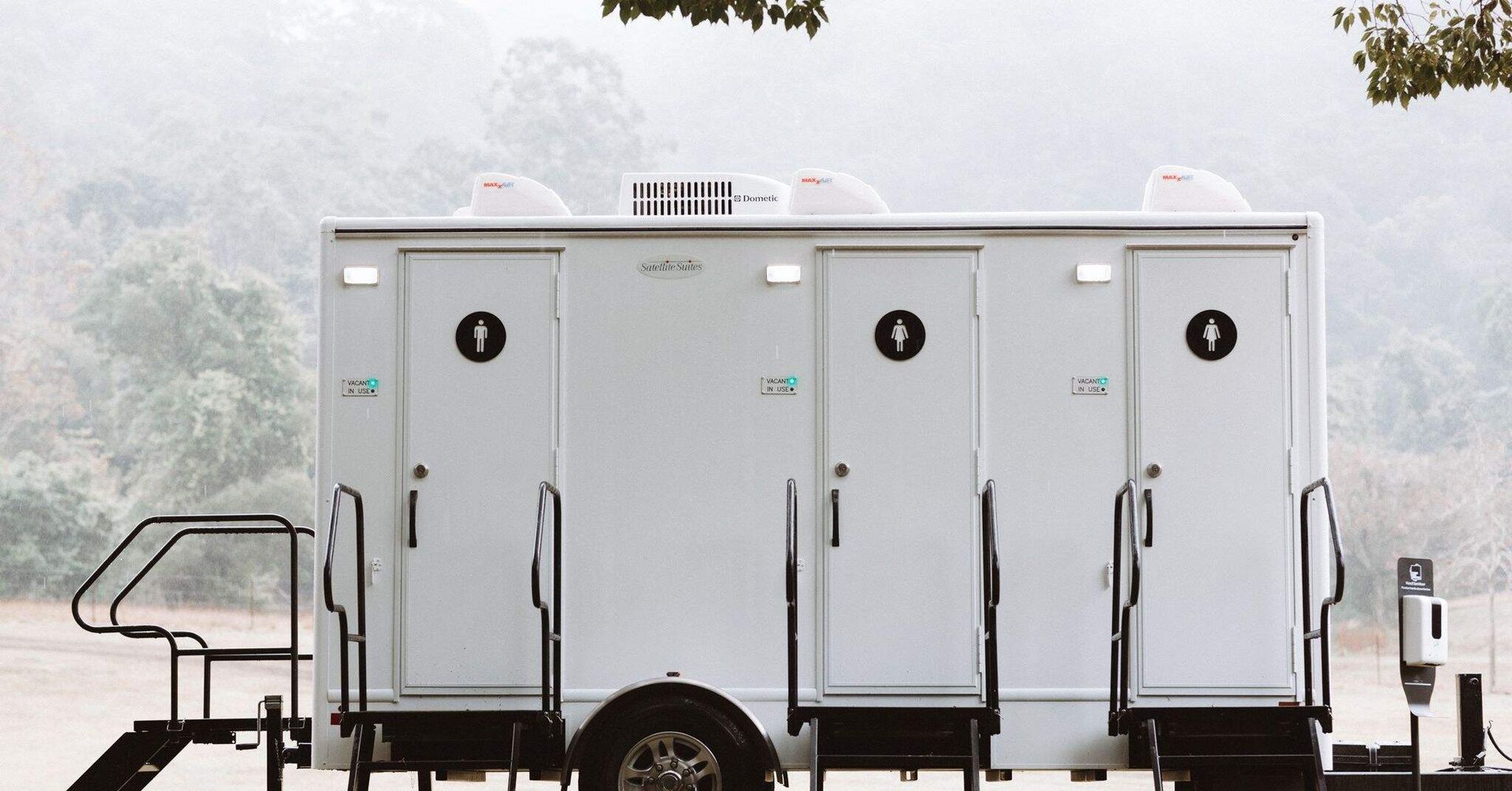 A White Trailer With Three Toilets on It is Parked in a Field — Absoloo Hire Pty Ltd in Newcastle, NSW