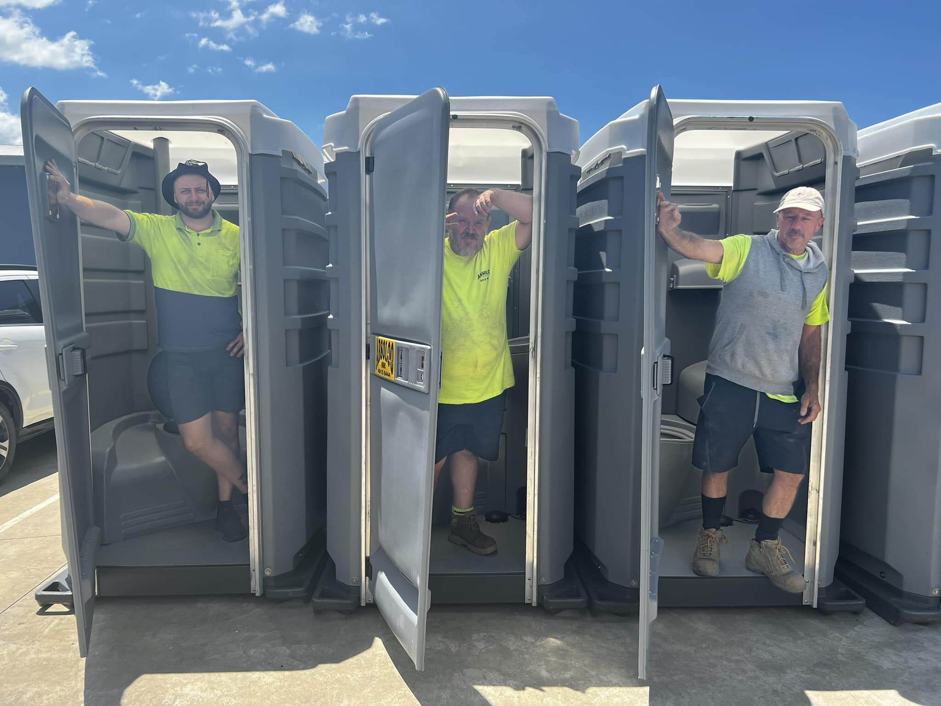 Three Men Are Standing in Portable Toilets in a Parking Lot — Absoloo Hire Pty Ltd in Forster, NSW