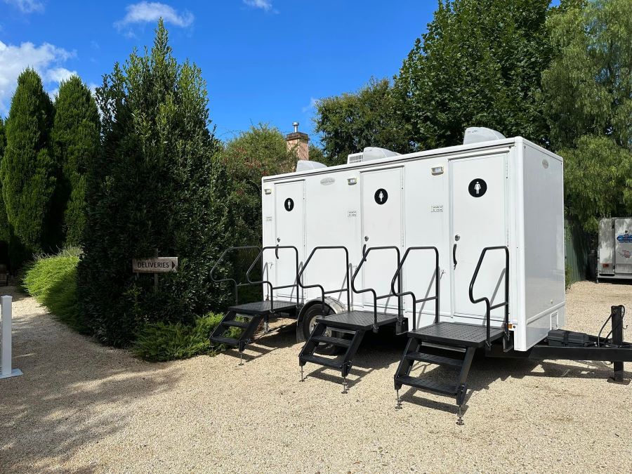 A Row of Portable Toilets Are Parked in a Gravel Lot — Absoloo Hire Pty Ltd in Taree, NSW