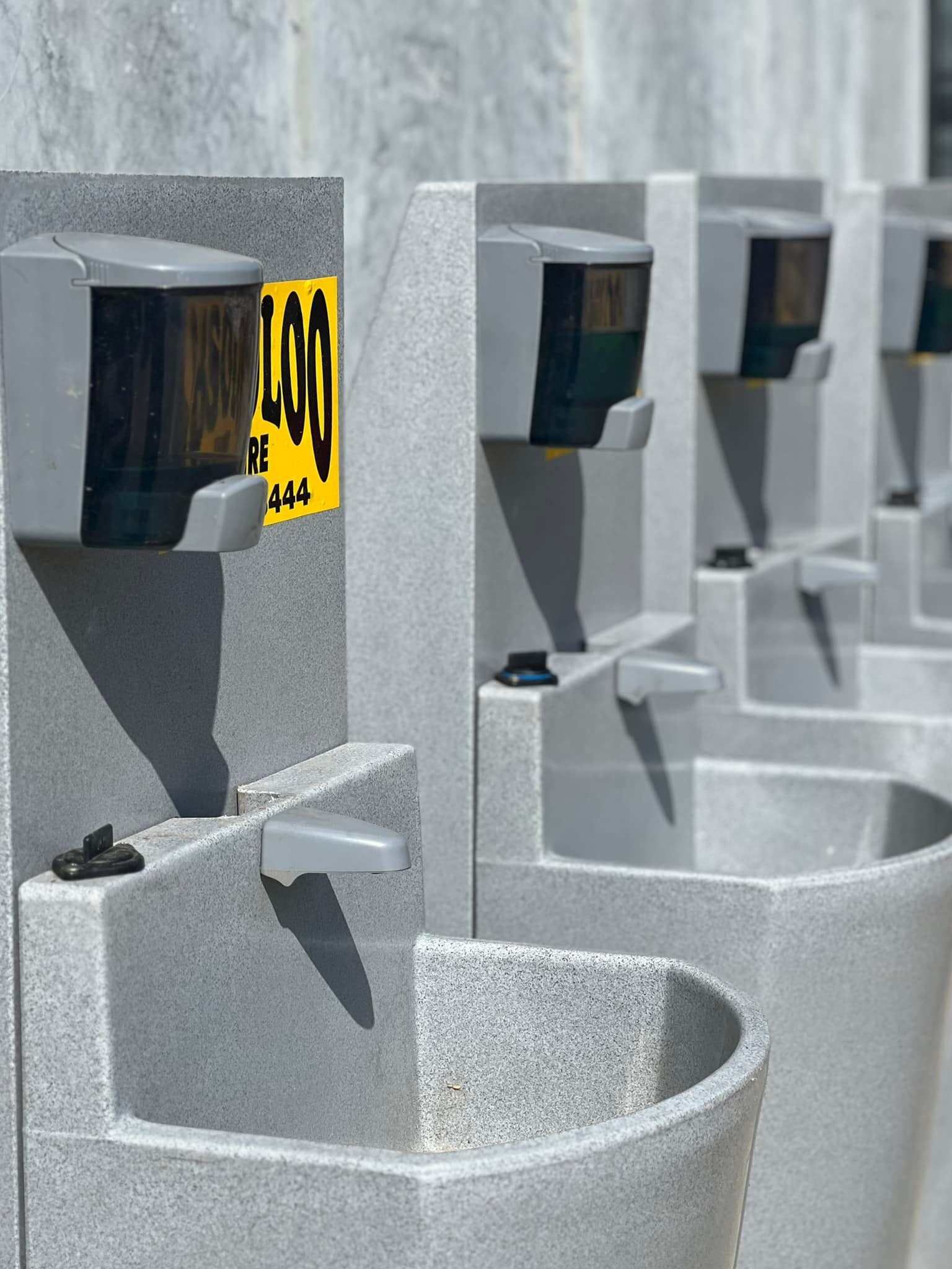 A Row of Concrete Sinks With Dispensers — Absoloo Hire Pty Ltd in Morisset, NSW