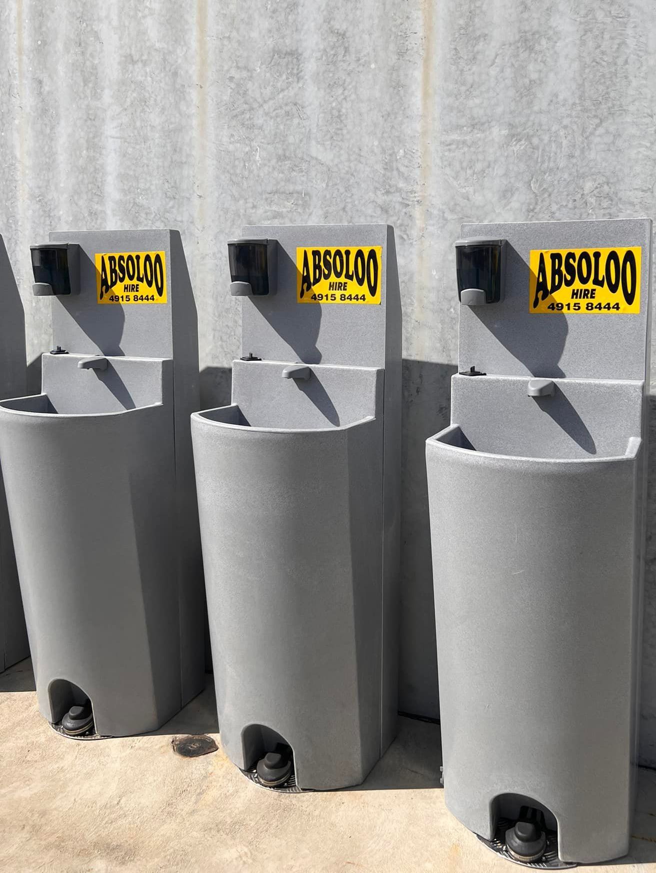 Three Gray Sinks With Yellow Signs on Them Are Lined Up Next to Each Other — Absoloo Hire Pty Ltd In Morisset, NSW