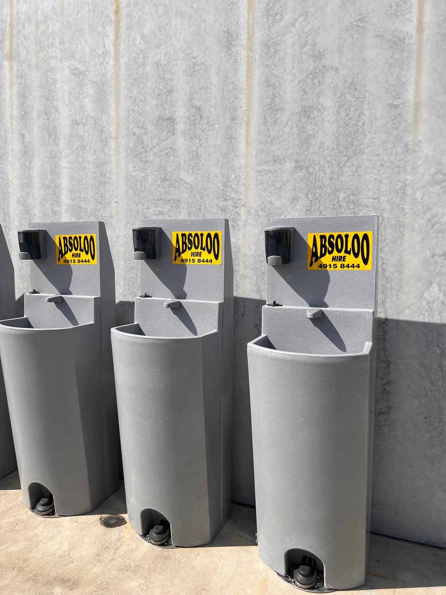 Row of Portable Sinks Are Lined Up in Front of a Concrete Wall — Absoloo Hire Pty Ltd in Morisset, NSW