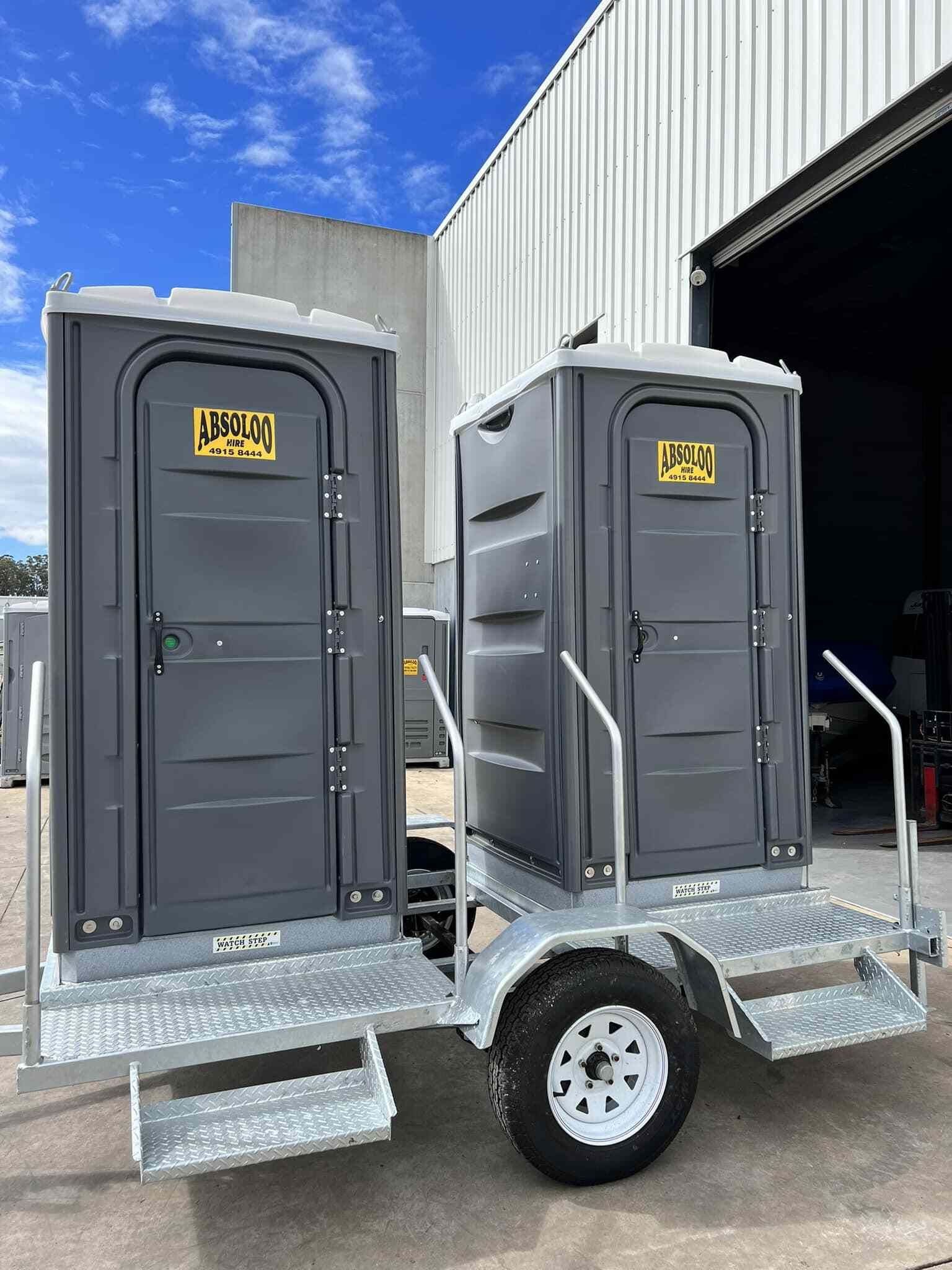 Two Portable Toilets on a Trailer Are Parked in Front of a Building — Absoloo Hire Pty Ltd in Wyong, NSW