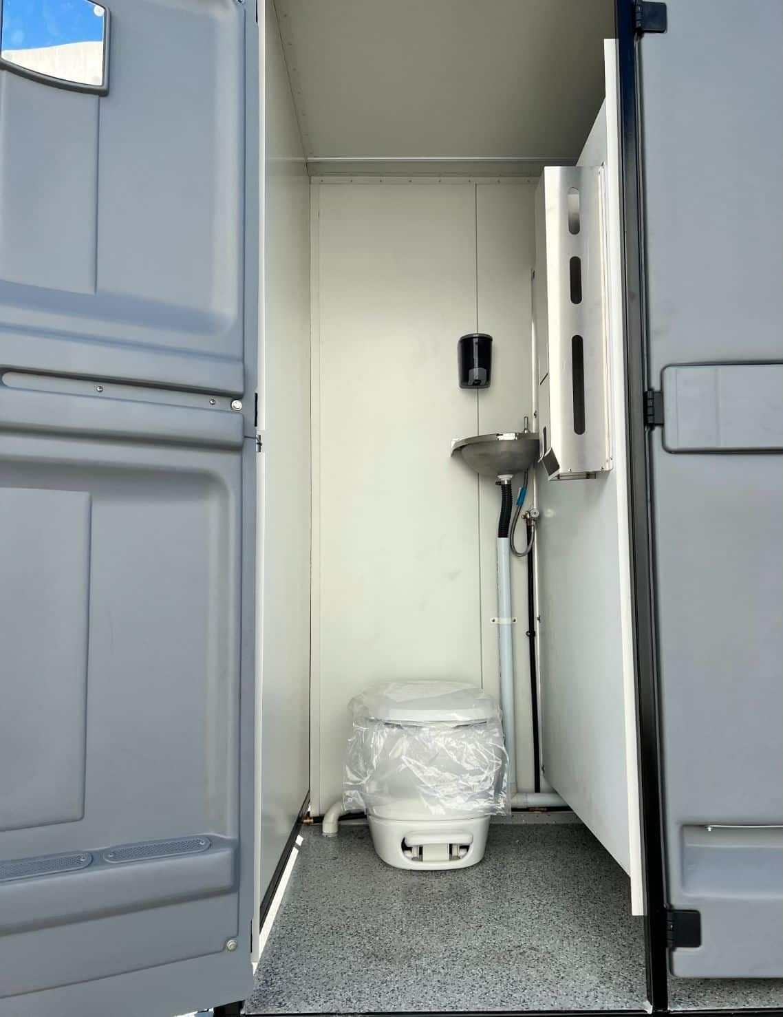 A Portable Toilet With the Door Open and a Sink — Absoloo Hire Pty Ltd In Morisset, NSW