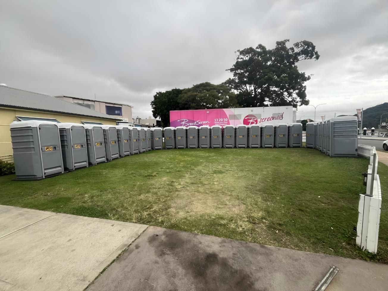 A Row of Portable Toilets Are Lined Up in a Grassy Field — Absoloo Hire Pty Ltd In Morisset, NSW