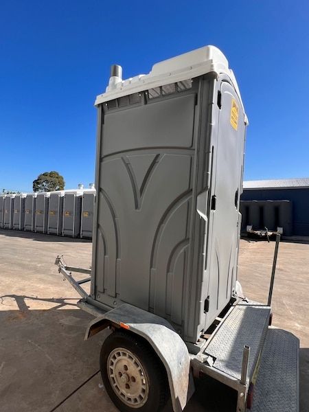 A Portable Toilet is on a Trailer in a Parking Lot — Absoloo Hire Pty Ltd in Wyong, NSW