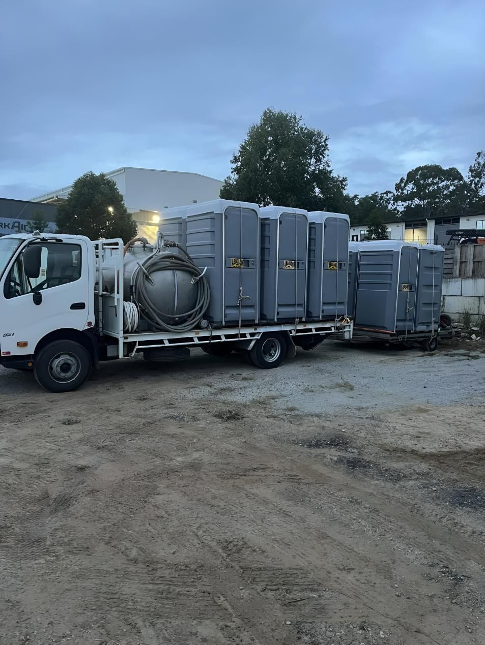 A White Truck is Carrying a Trailer Full of Portable Toilets. — Absoloo Hire Pty Ltd In Morisset, NSW