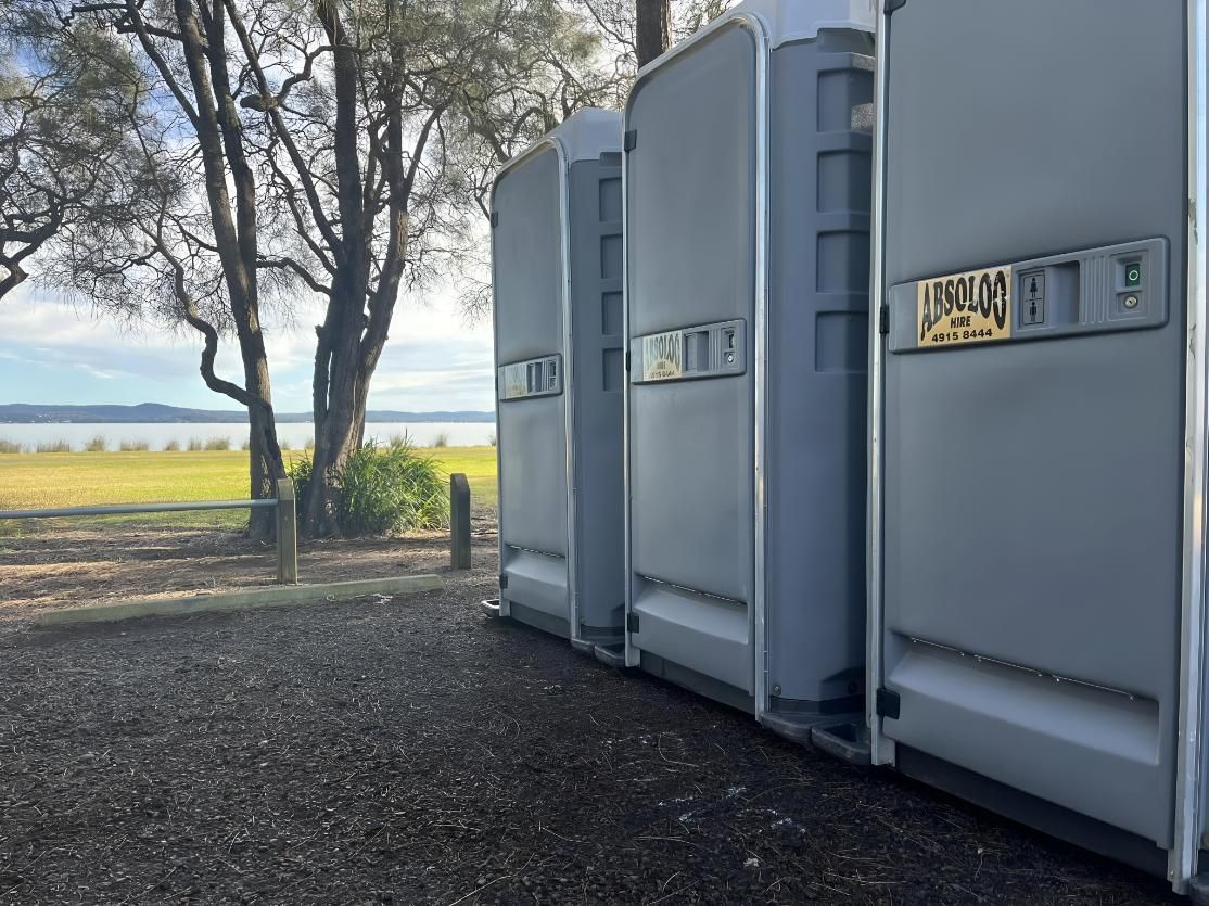 A Row of Portable Toilets Are Lined Up Next to Each Other — Absoloo Hire Pty Ltd In Morisset, NSW