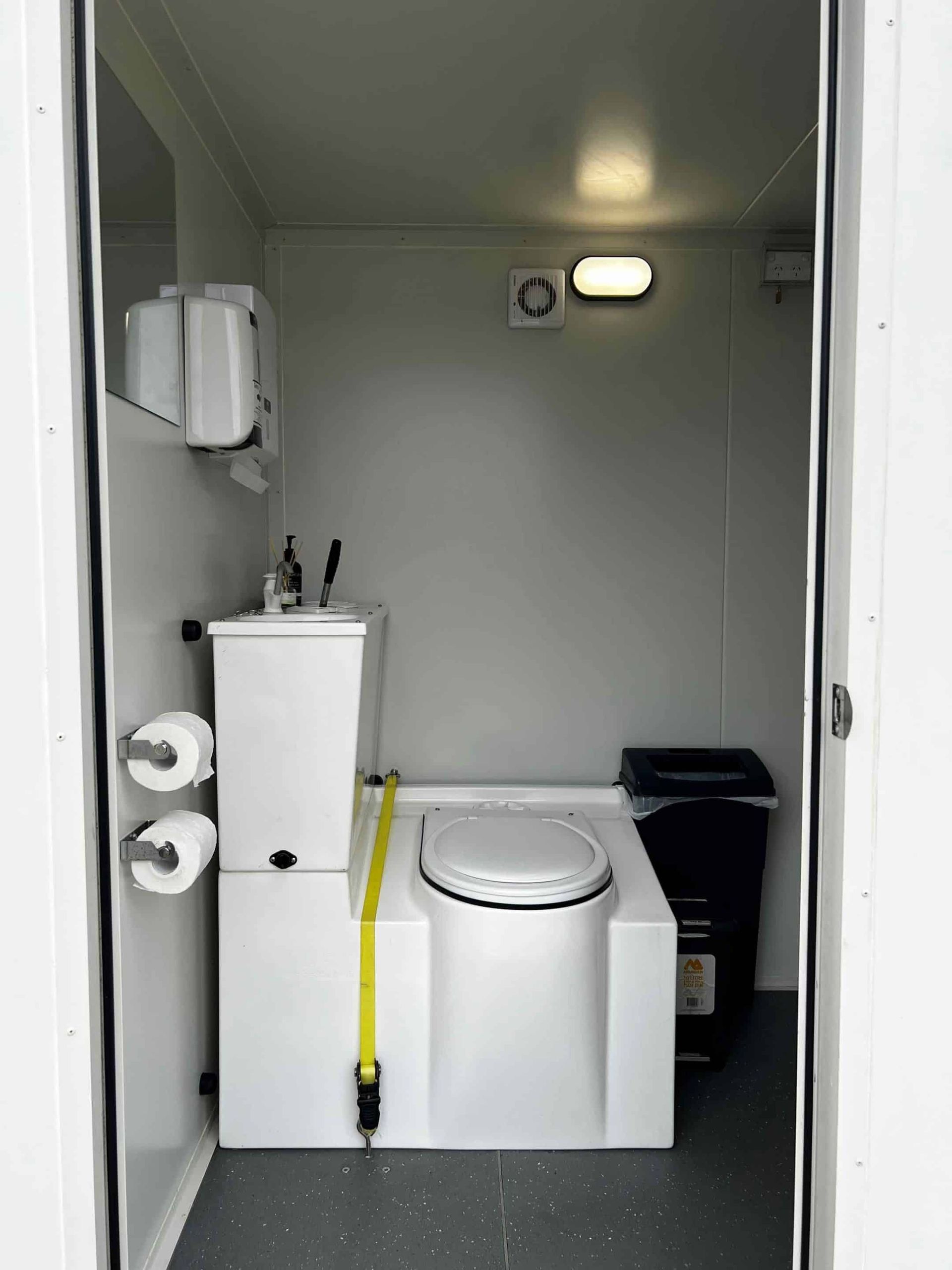 A Bathroom With a Toilet and a Trash Can — Absoloo Hire Pty Ltd in Port Macquarie, NSW
