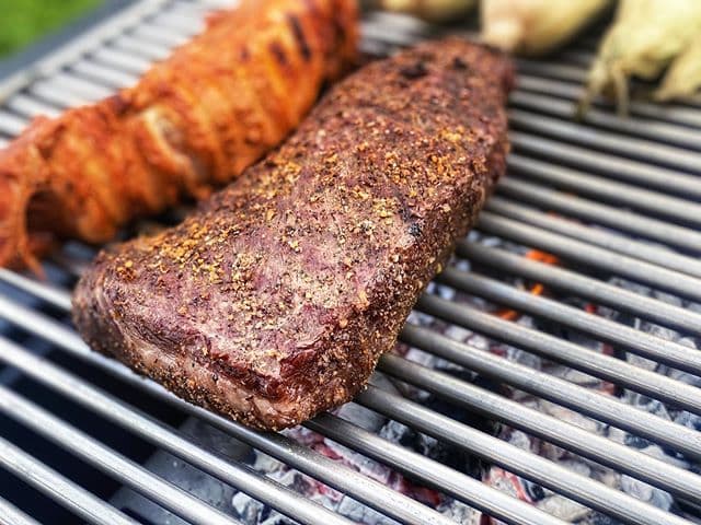 Closeup of a steak being cooked on a charcoal grill