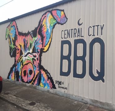 Image of mural on wall of a  colorful Pig with the words Central City BBQ restaurant in New Orleans