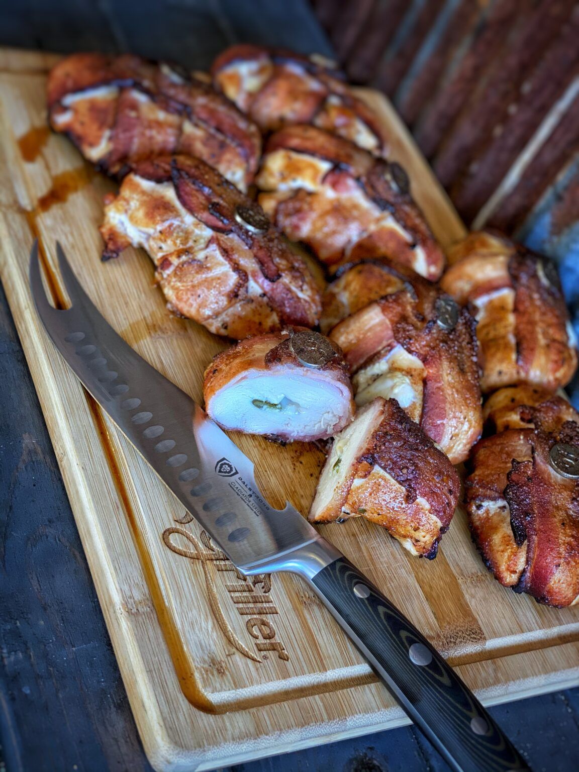 chicken griller recipe, bacon-wrapped grilled chicken with jalapenos and cheese sliced on cutting board with a knife