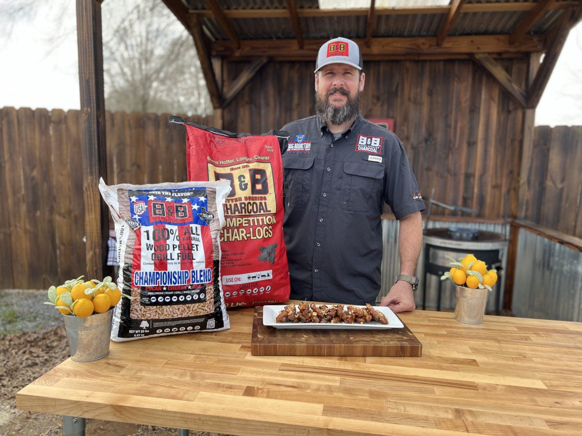 Pitmaster Marcio Borguezan with a plate of his PB&J Wings & a bags of B&B Char-Logs and B&B Championship blend pellets