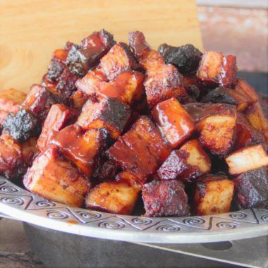 Grilled cubes of charred candied pork belly piled high in a bowl