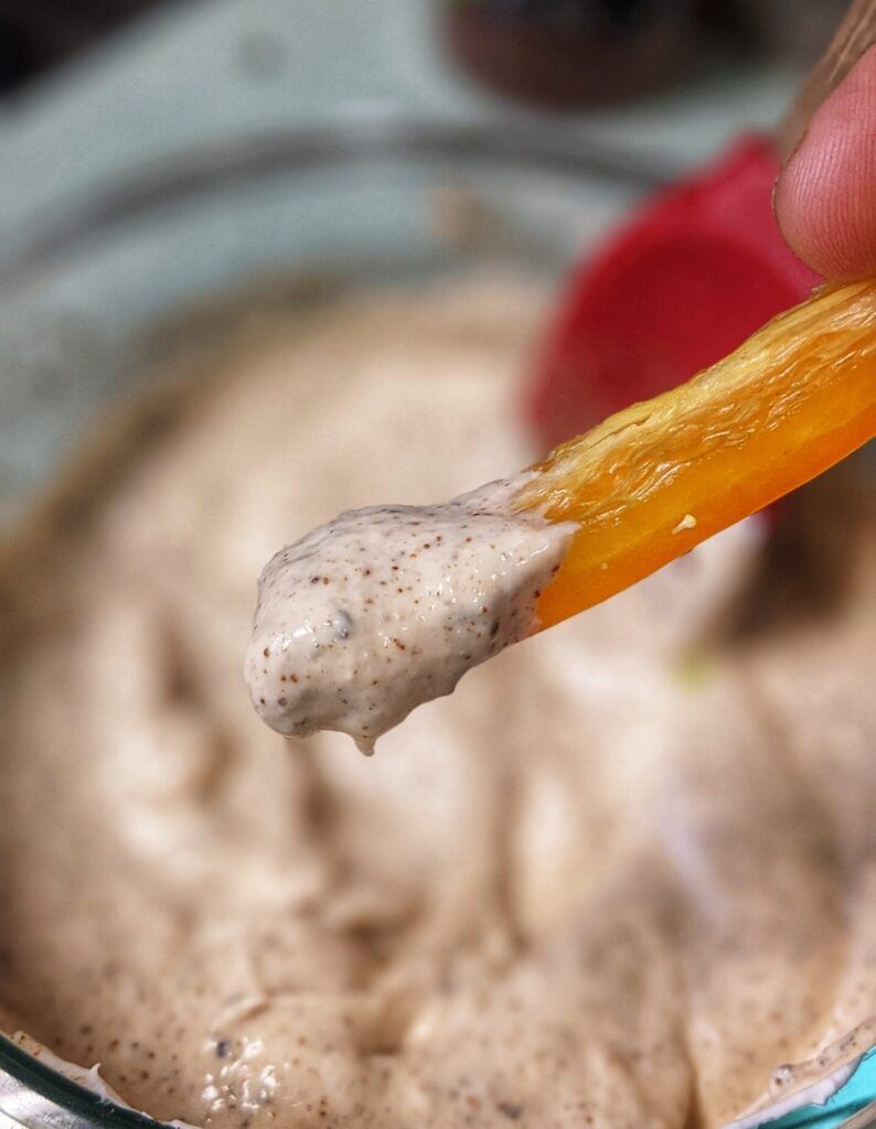 closeup dipping yellow bell pepper into chipotle dip