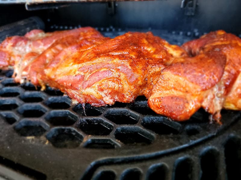 seasoned pork butt cooking on the grill