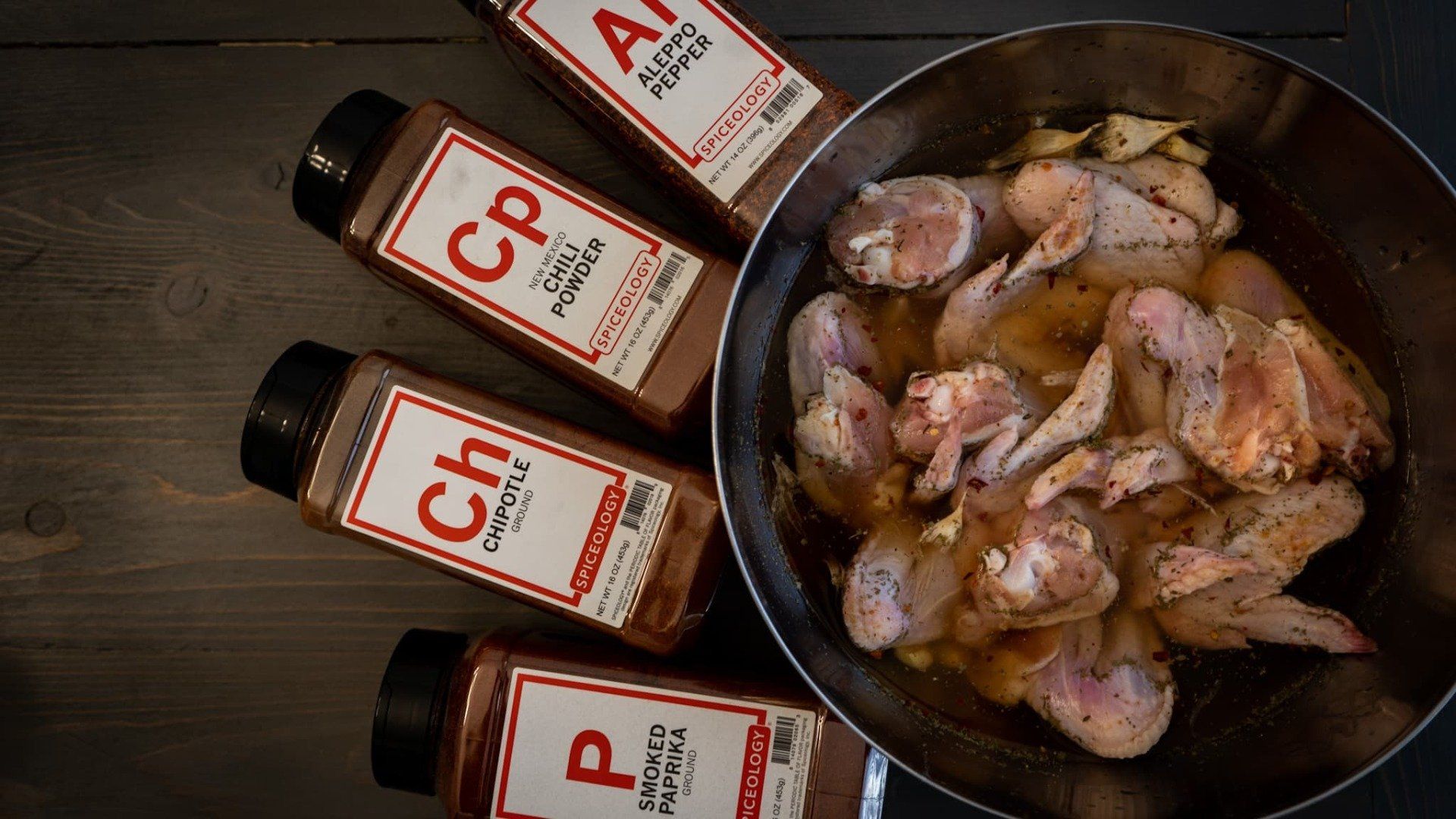 chicken wings brining in a bowl with spice bottles