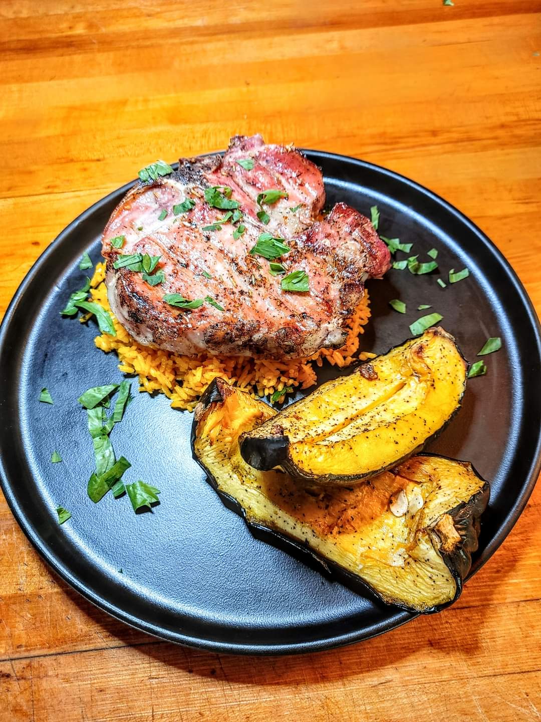 Grilled pork chop on bed or rice with grilled squash on plate