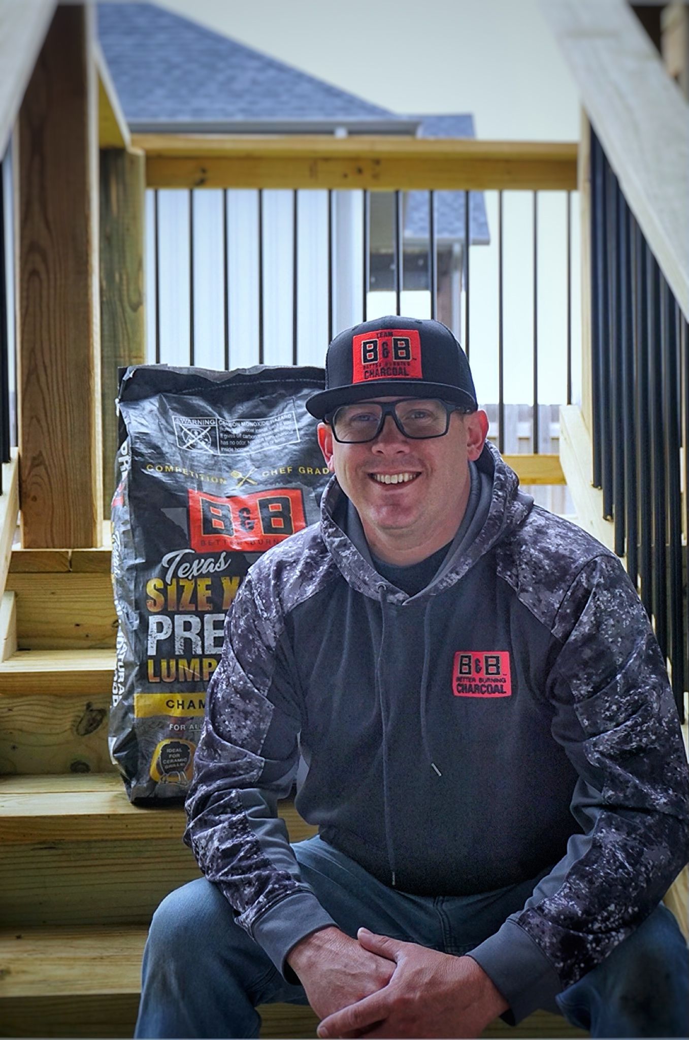 B&B Ambassador and Pitmaster Mark Lambert is holding a trophy on stage at a BBQ competition