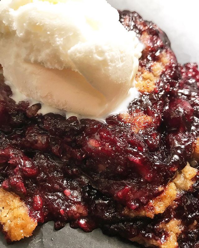 Closeup of blackberry cobbler with scoop of ice cream melting  on top