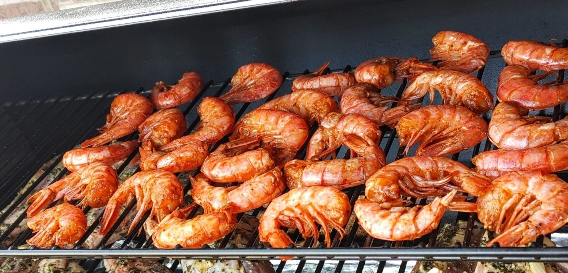 Grill covered with red unpeeled shrimp cooking