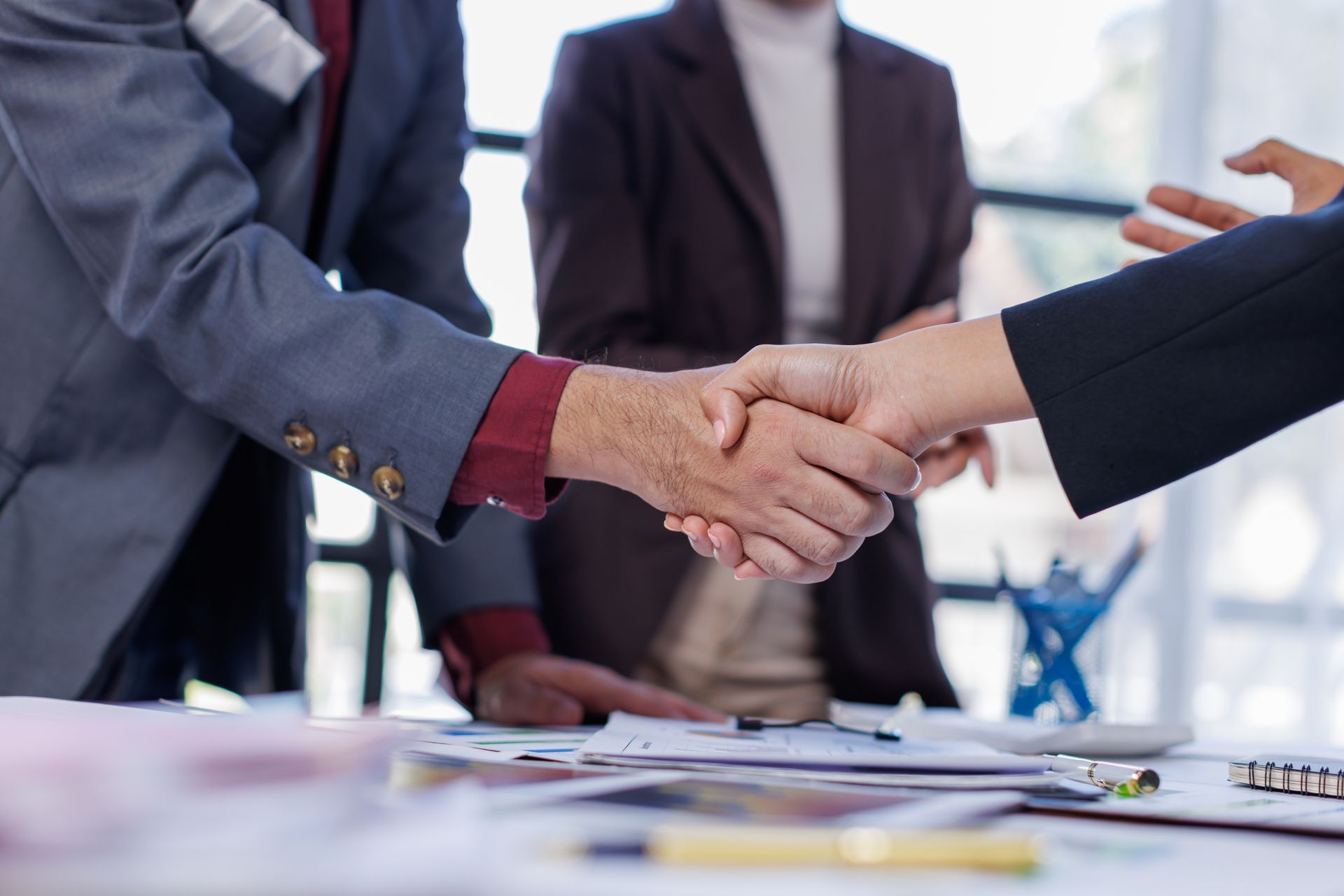 A group of business people are shaking hands in an office.