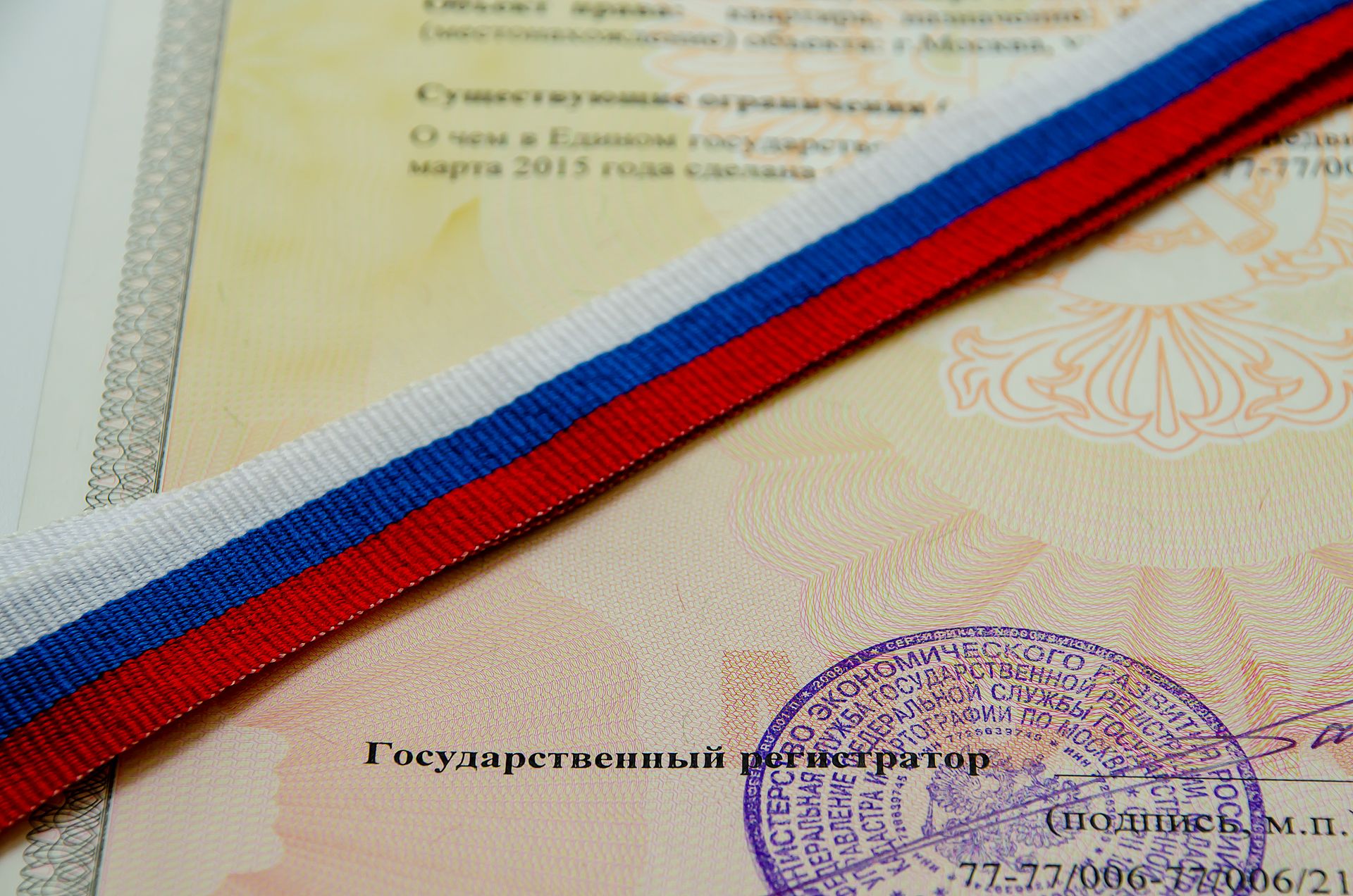 A red white and blue ribbon is laying on top of a certificate