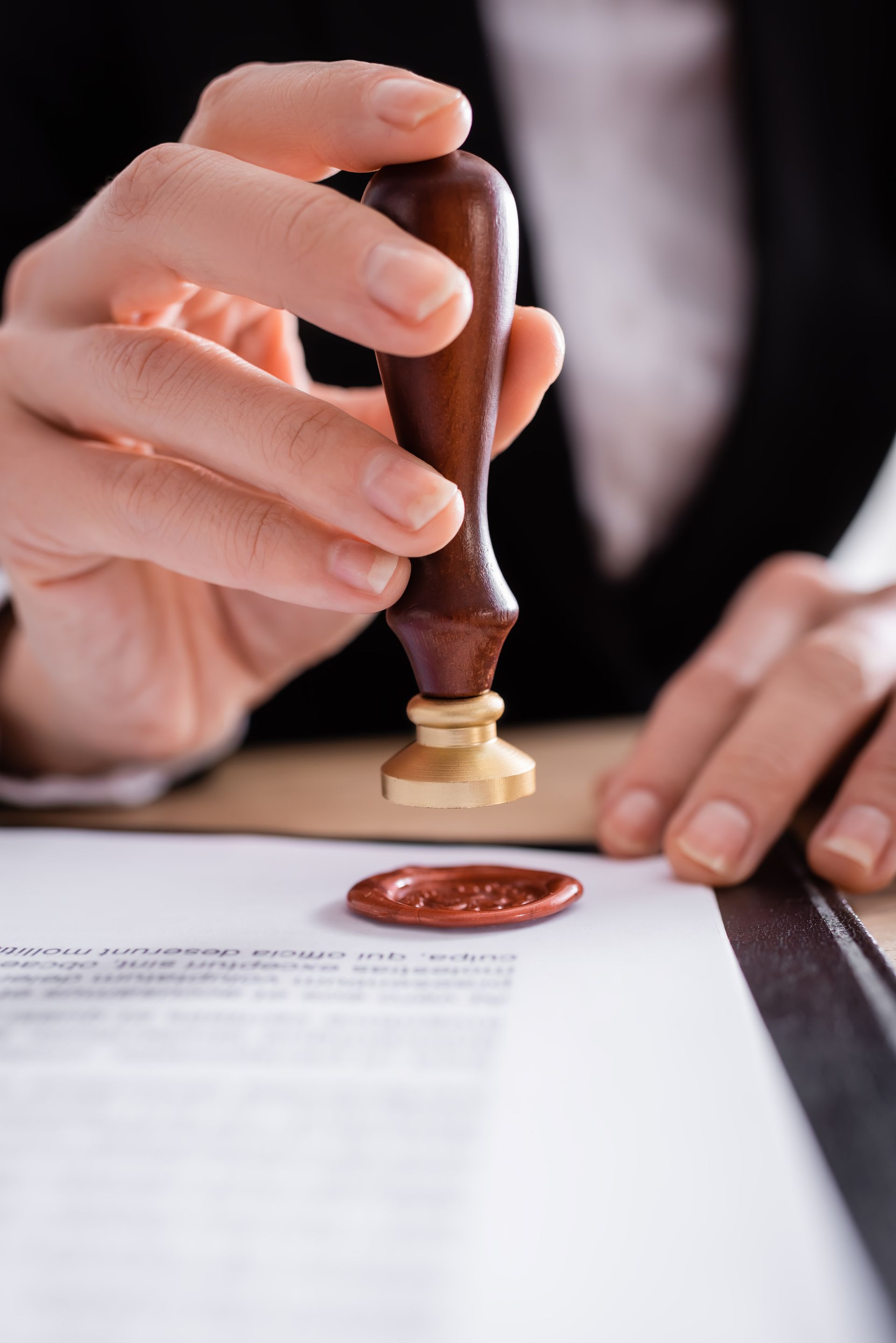 A person is stamping a document with a wax seal.