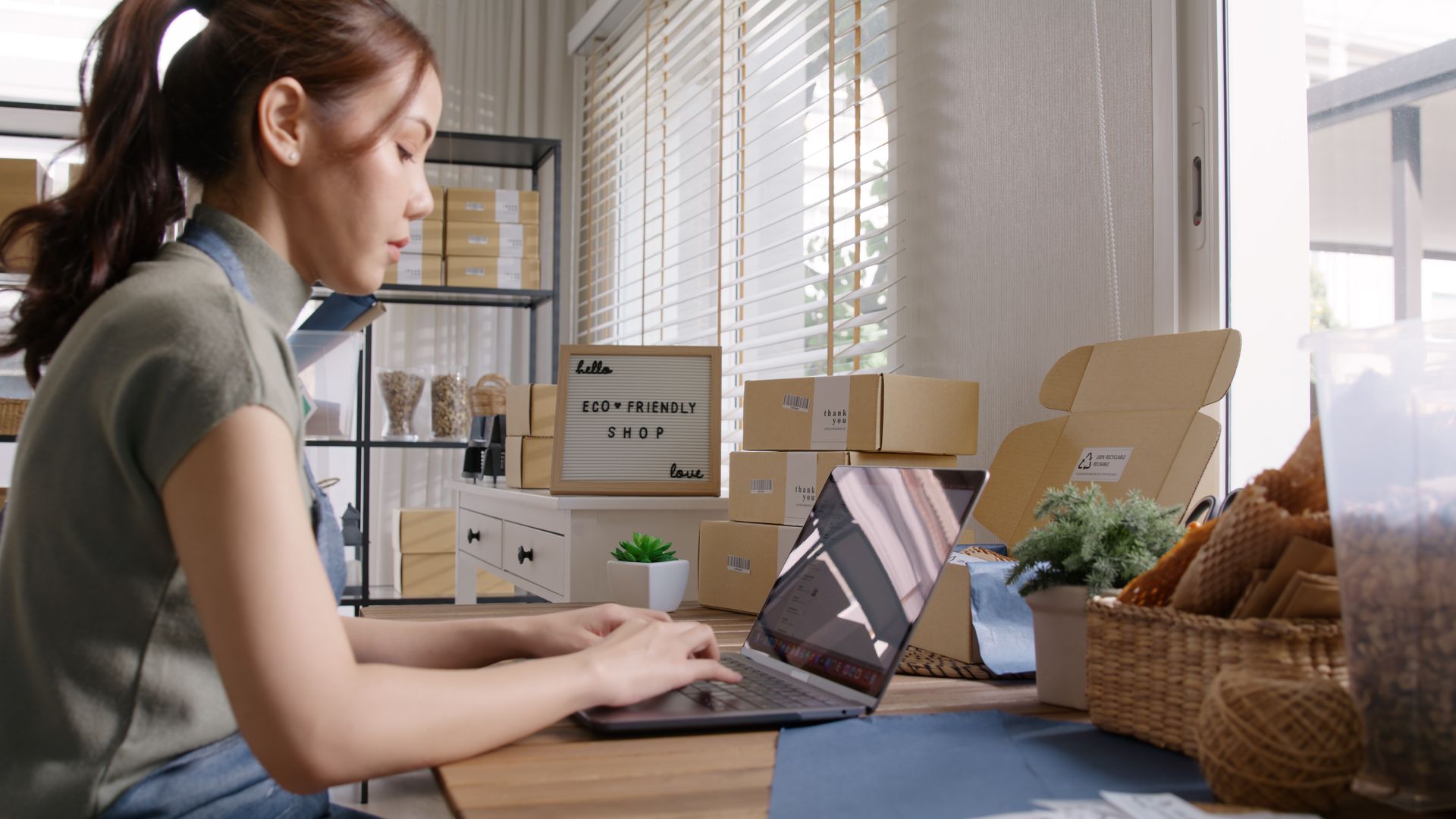 A woman is sitting at a desk using a laptop computer.
