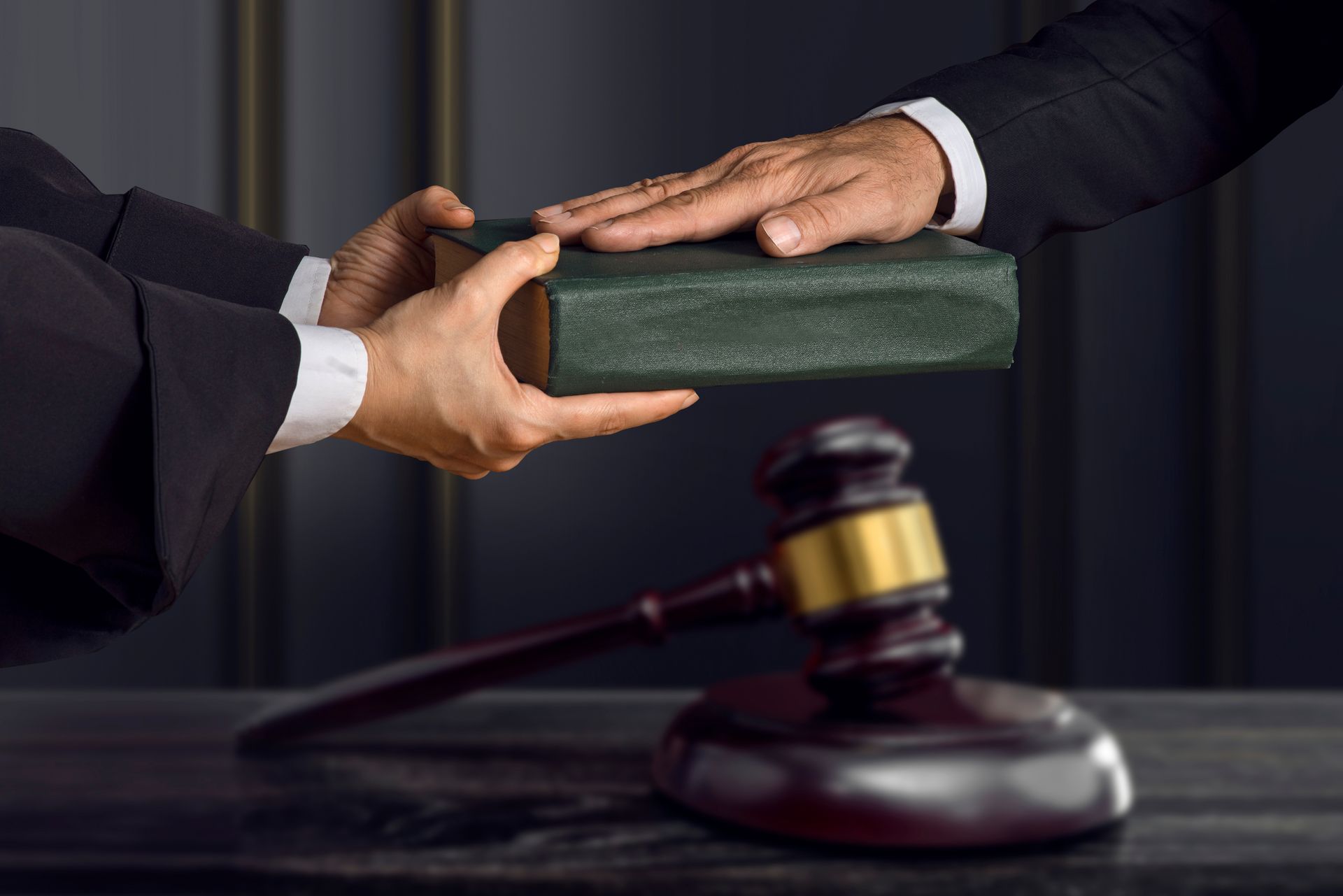 A judge is giving a book to a lawyer in front of a gavel.
