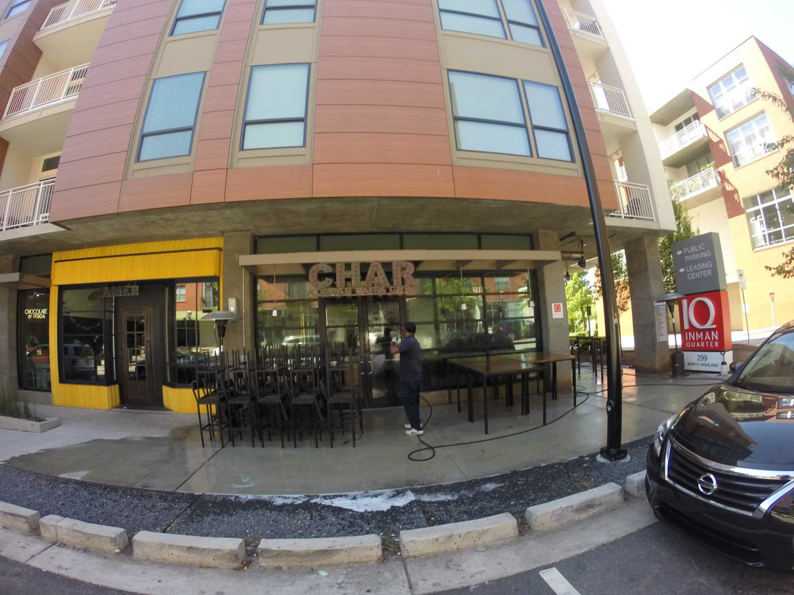 Street-level view of a café storefront with outdoor seating in a modern apartment building.