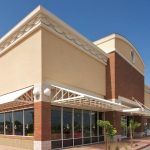 Modern brick-and-beige building exterior with glass windows and an awning entrance